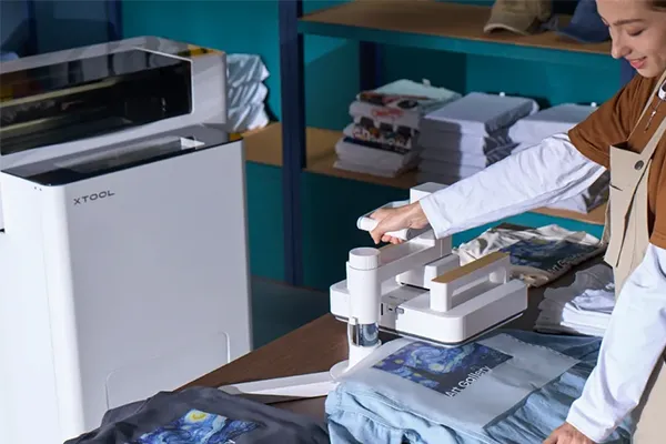 DTF Drucker Der DTF Drucker von xTool steht mit passenden Transferpressen in einem Arbeitsraum.