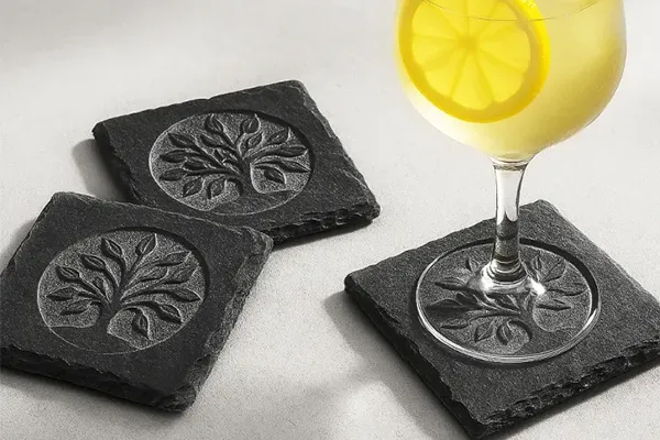Ein Baummotiv ist auf verschiedenen Schieferplatten graviert, welche als Untersetzer dienen.