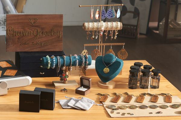 Auf dem Bild ist eine Auswahl an gelasertem Schmuck auf einem hellen Holztisch zu sehen.